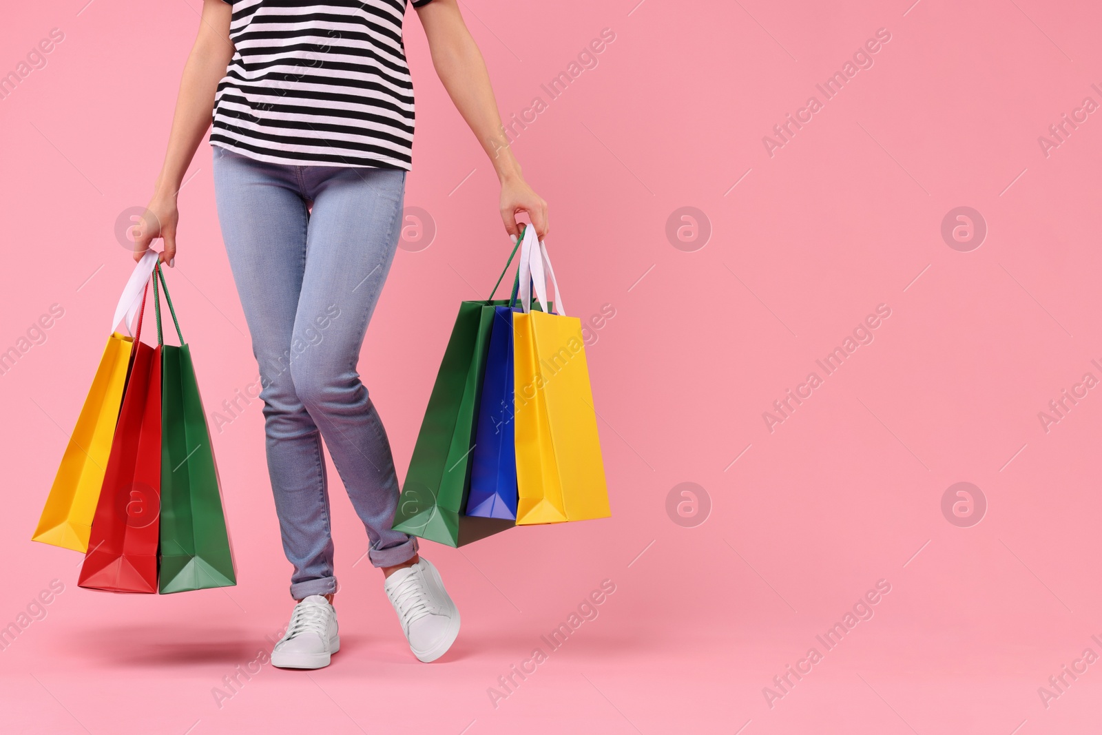 Photo of Woman with shopping bags on pink background, closeup. Space for text