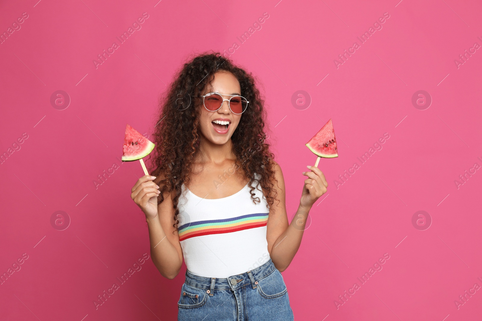 Photo of Beautiful young African American woman with pieces of watermelon on crimson background