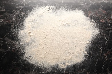 Photo of Pile of flour on black marble table, top view