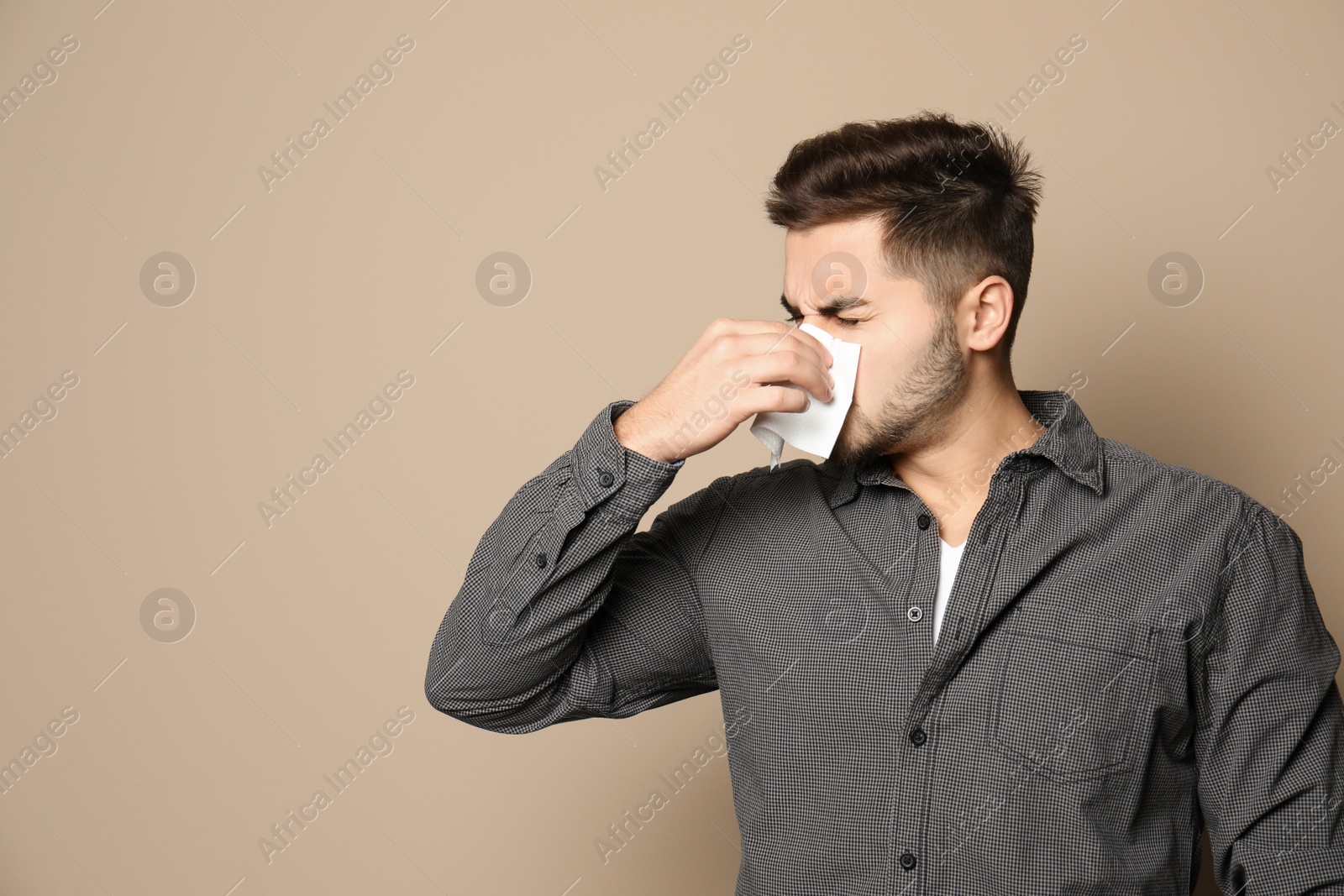 Photo of Handsome young man blowing nose against color background. Space for text