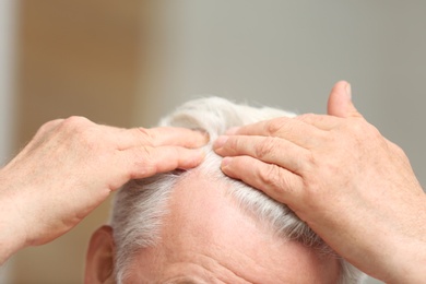 Senior man with hair loss problem indoors, closeup