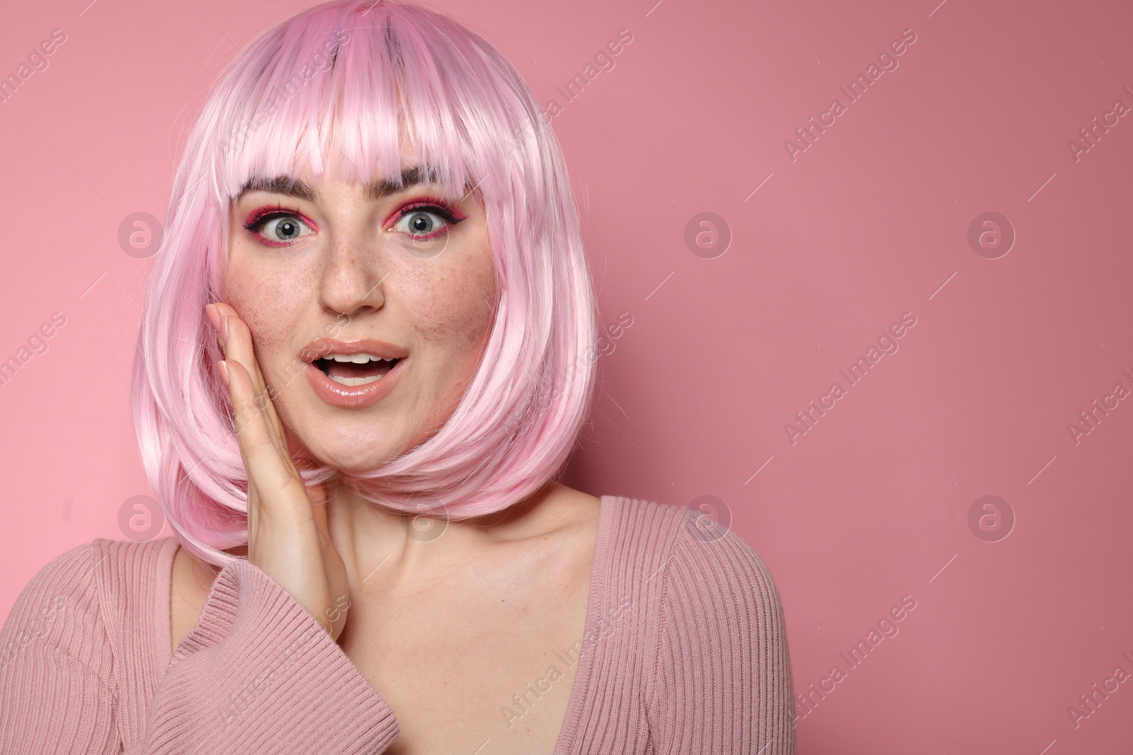 Photo of Emotional woman with bright makeup and fake freckles on pink background. Space for text