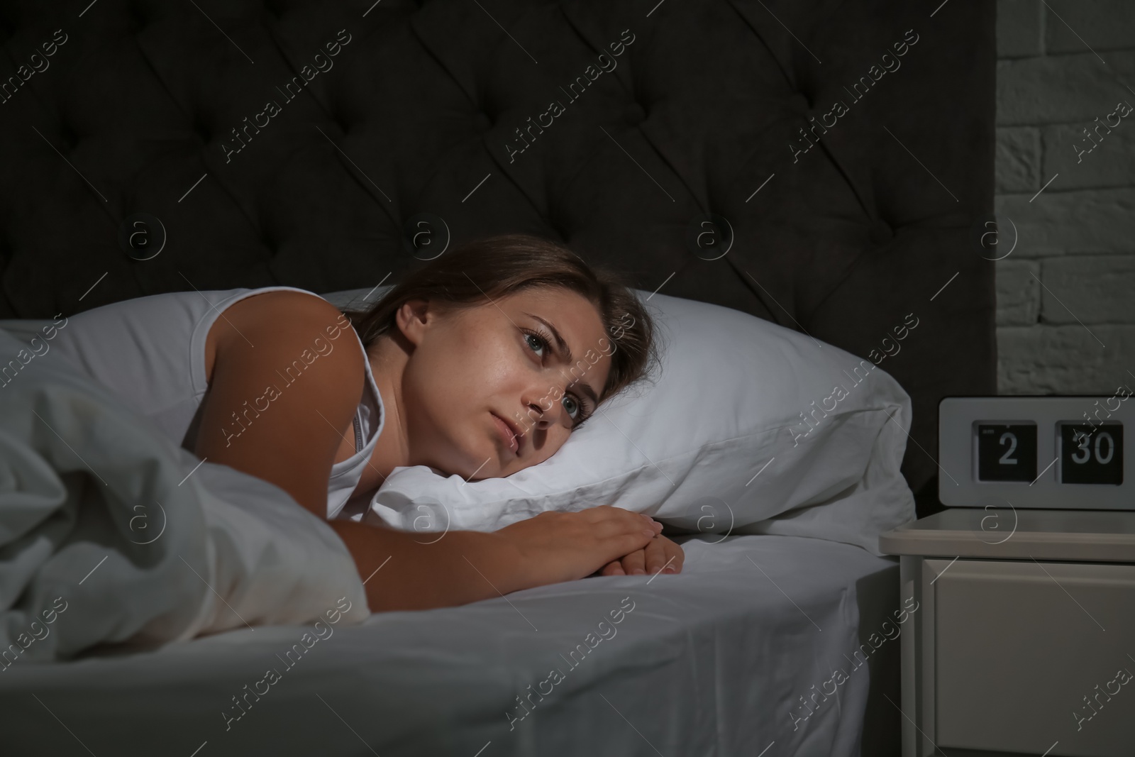 Photo of Young woman suffering from insomnia in bed at home