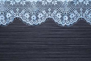 Photo of Light blue lace on black table, top view. Space for text