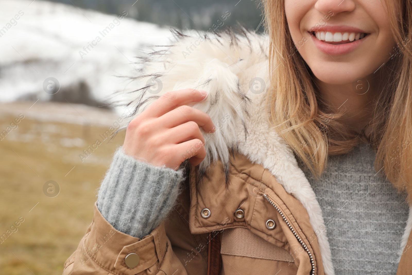 Photo of Young woman in warm clothes near snowy hill, closeup. Winter vacation