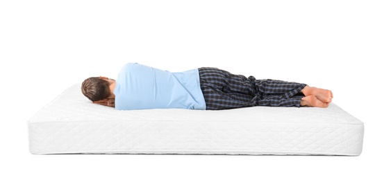 Young man lying on mattress against white background