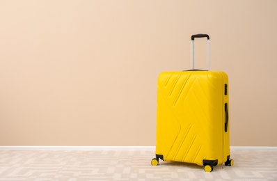 Modern suitcase on floor near light wall. Space for text