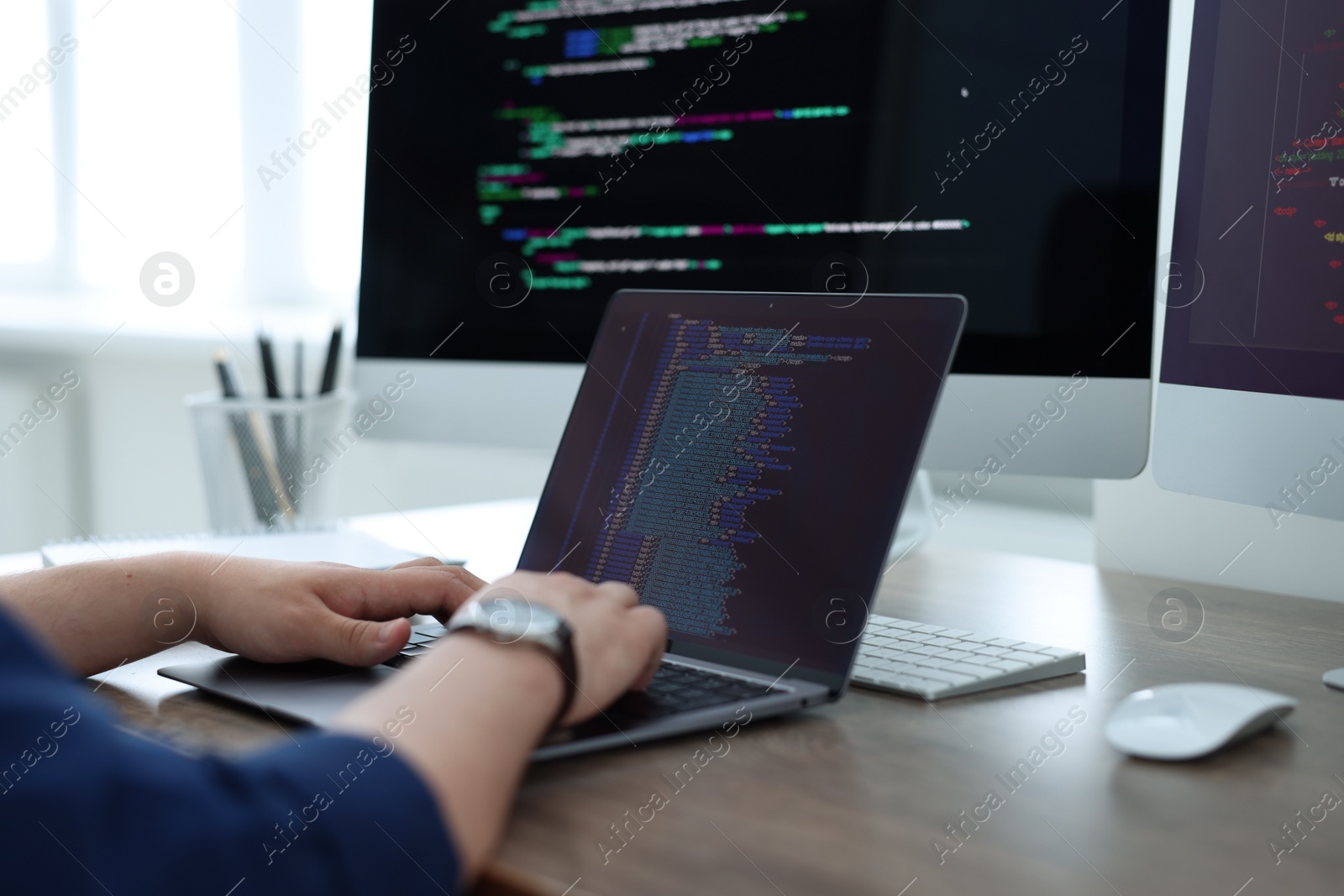 Photo of Programmer working with laptop at desk in office, closeup
