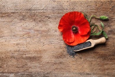 Flat lay composition with poppy seeds and flower on wooden table, space for text