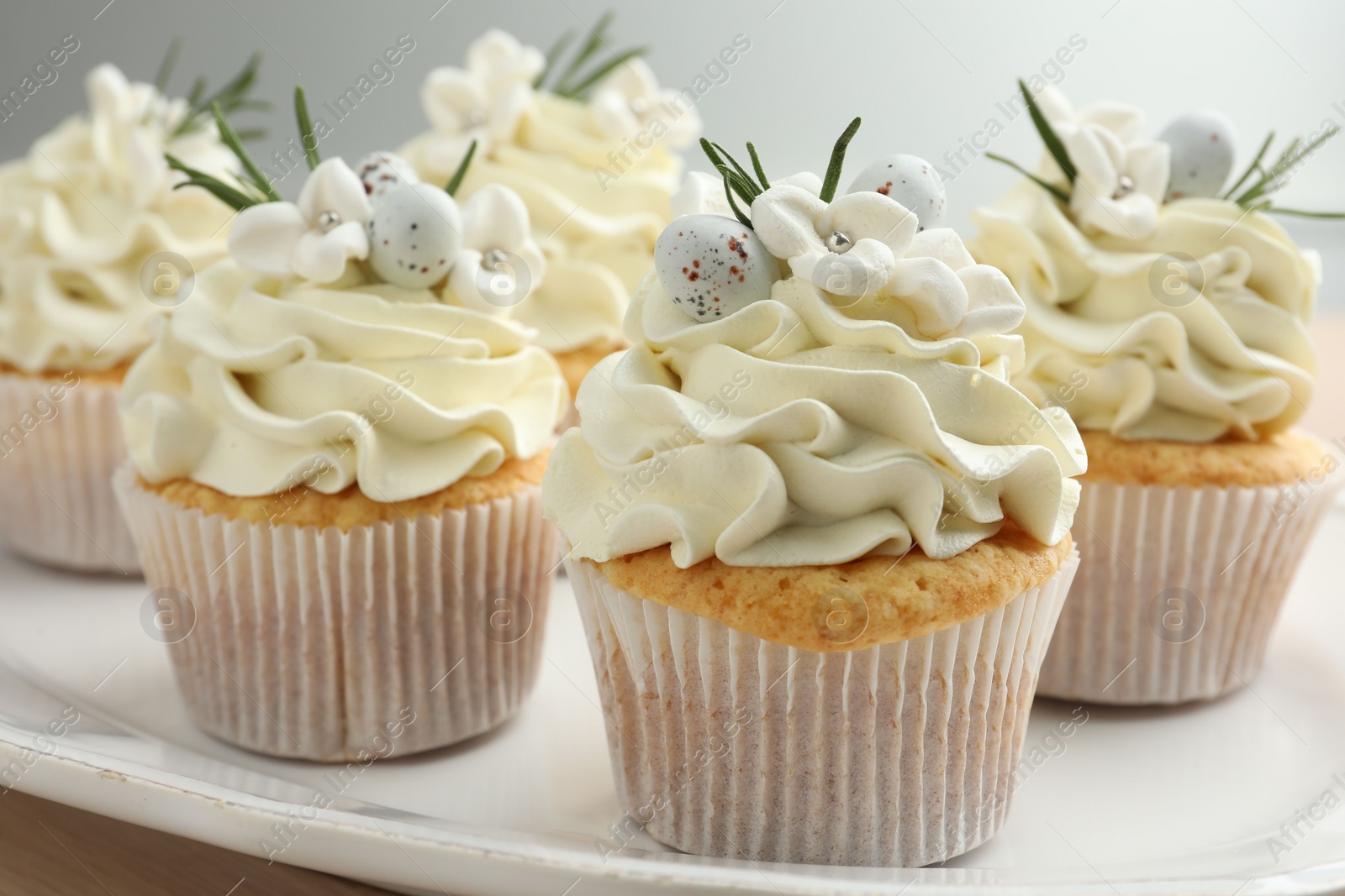 Photo of Tasty Easter cupcakes with vanilla cream on table, closeup