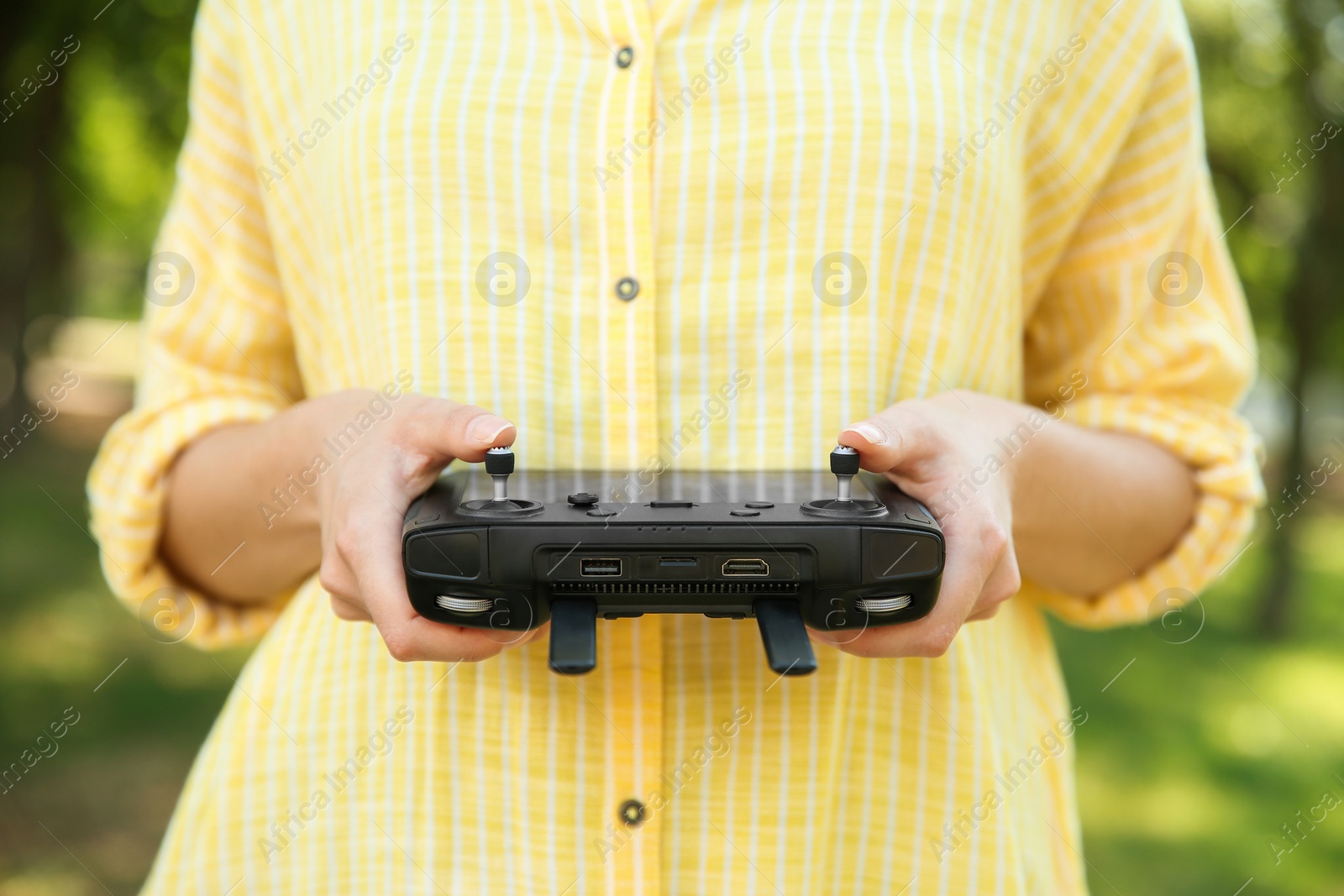 Photo of Woman holding new modern drone controller outdoors, closeup of hands