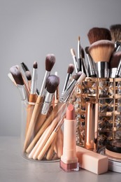 Photo of Set of professional brushes and makeup products on table against grey background