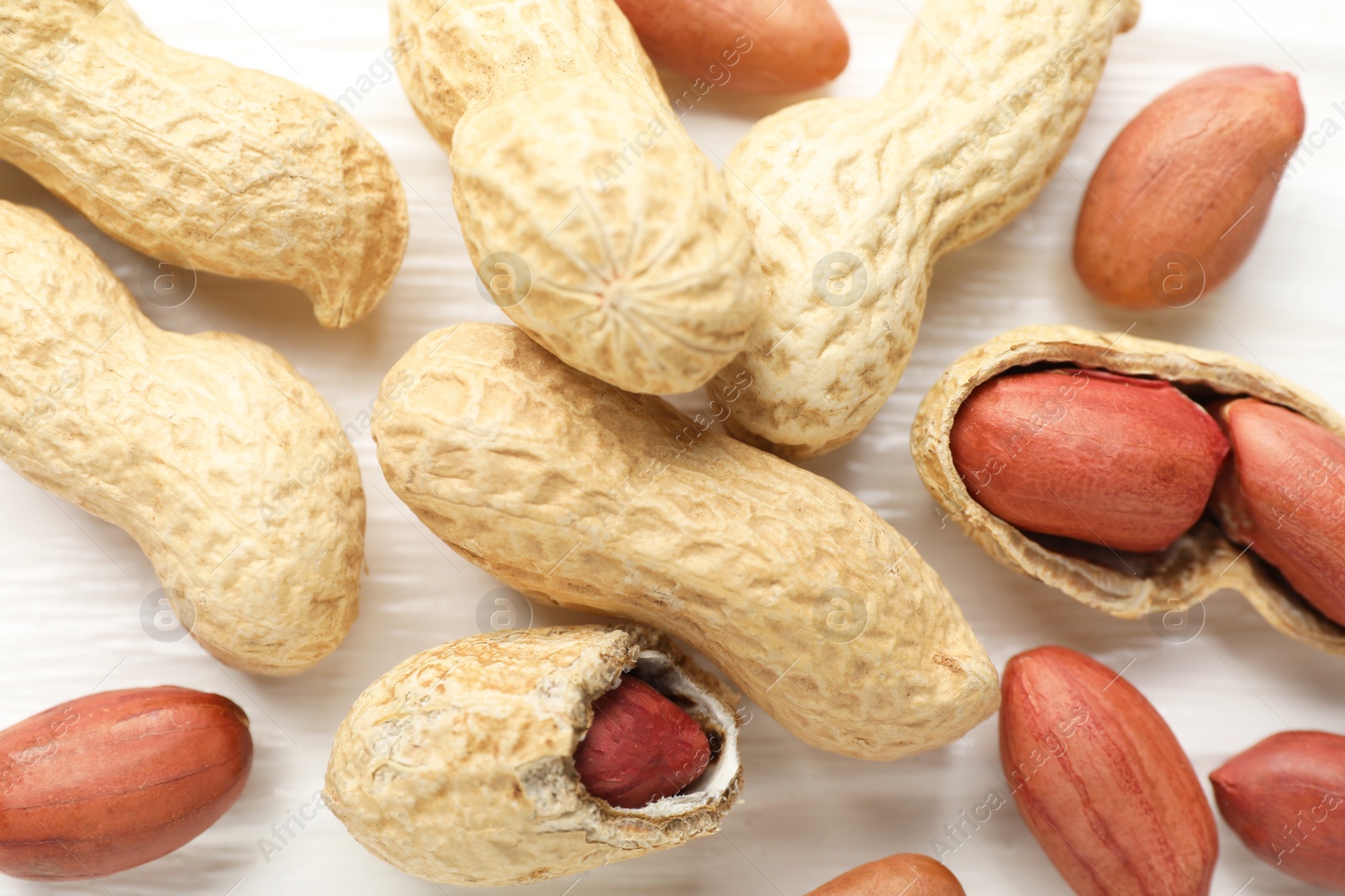 Photo of Fresh unpeeled peanuts on white wooden table, flat lay