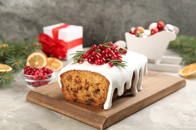 Traditional classic Christmas cake decorated with cranberries, pomegranate seeds and rosemary on light table
