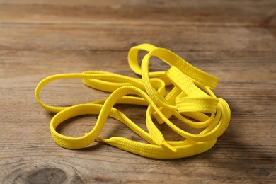 Photo of Yellow shoelace on wooden background. Stylish accessory