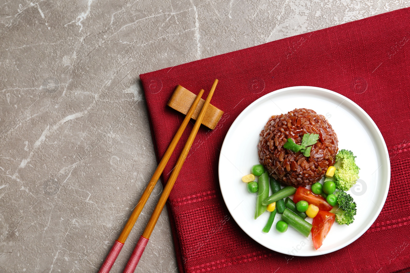 Photo of Plate of boiled brown rice with vegetables served on table, top view. Space for text