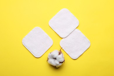 Soft clean cotton pads and flower on yellow background, flat lay