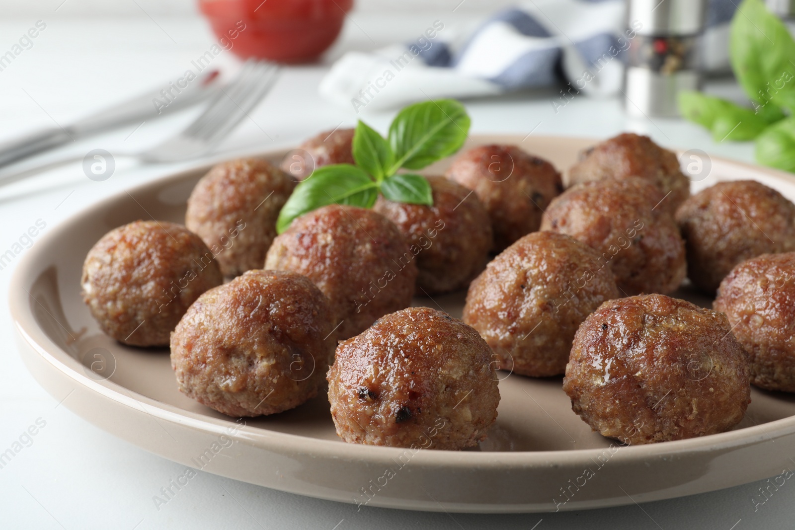 Photo of Tasty cooked meatballs with basil on plate, closeup