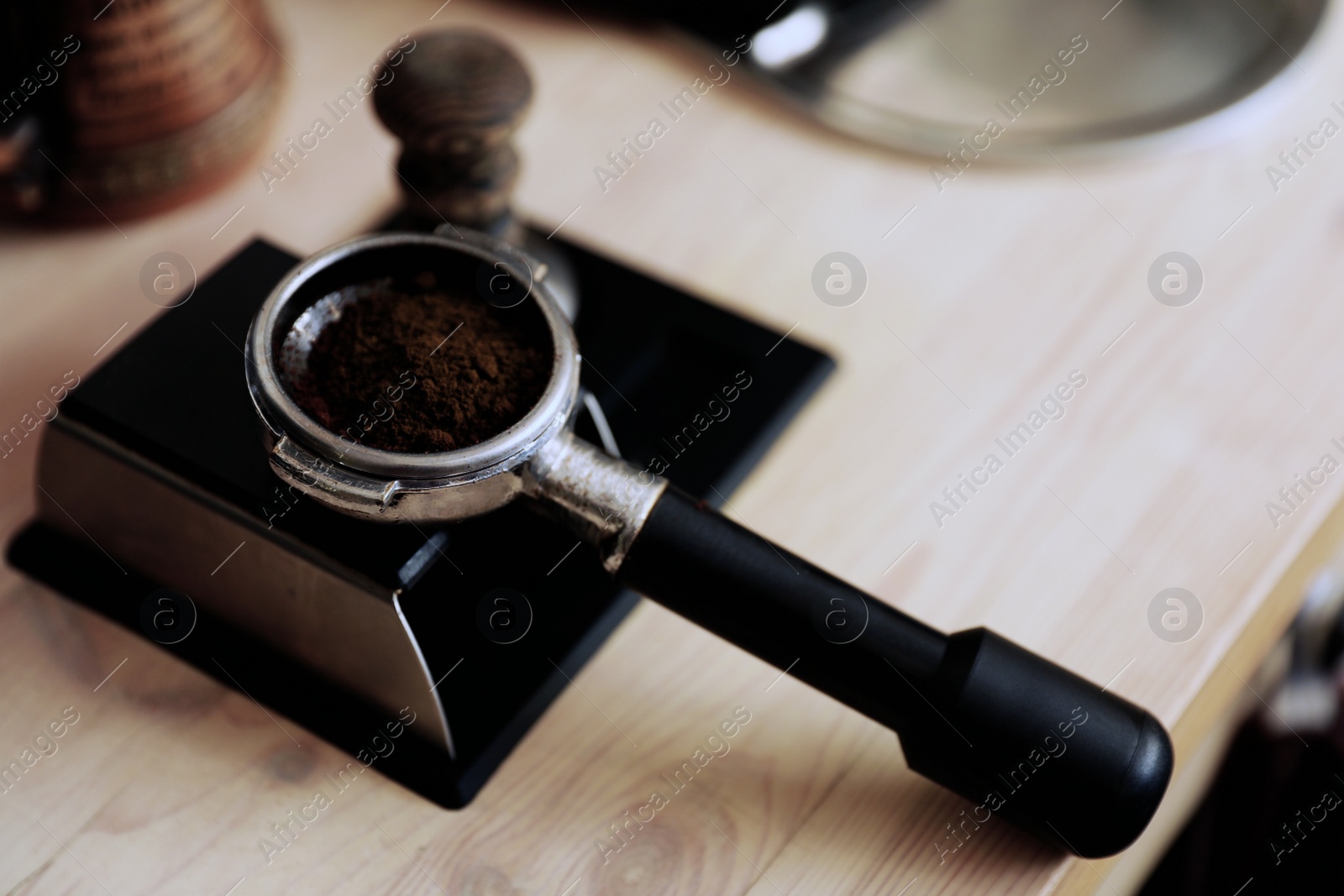 Photo of Portafilter with roasted ground coffee on table