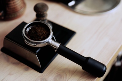 Portafilter with roasted ground coffee on table