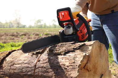 Photo of Man sawing wooden log on sunny day, closeup