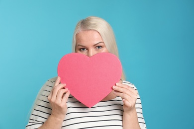 Photo of Portrait of mature woman with decorative heart on color background