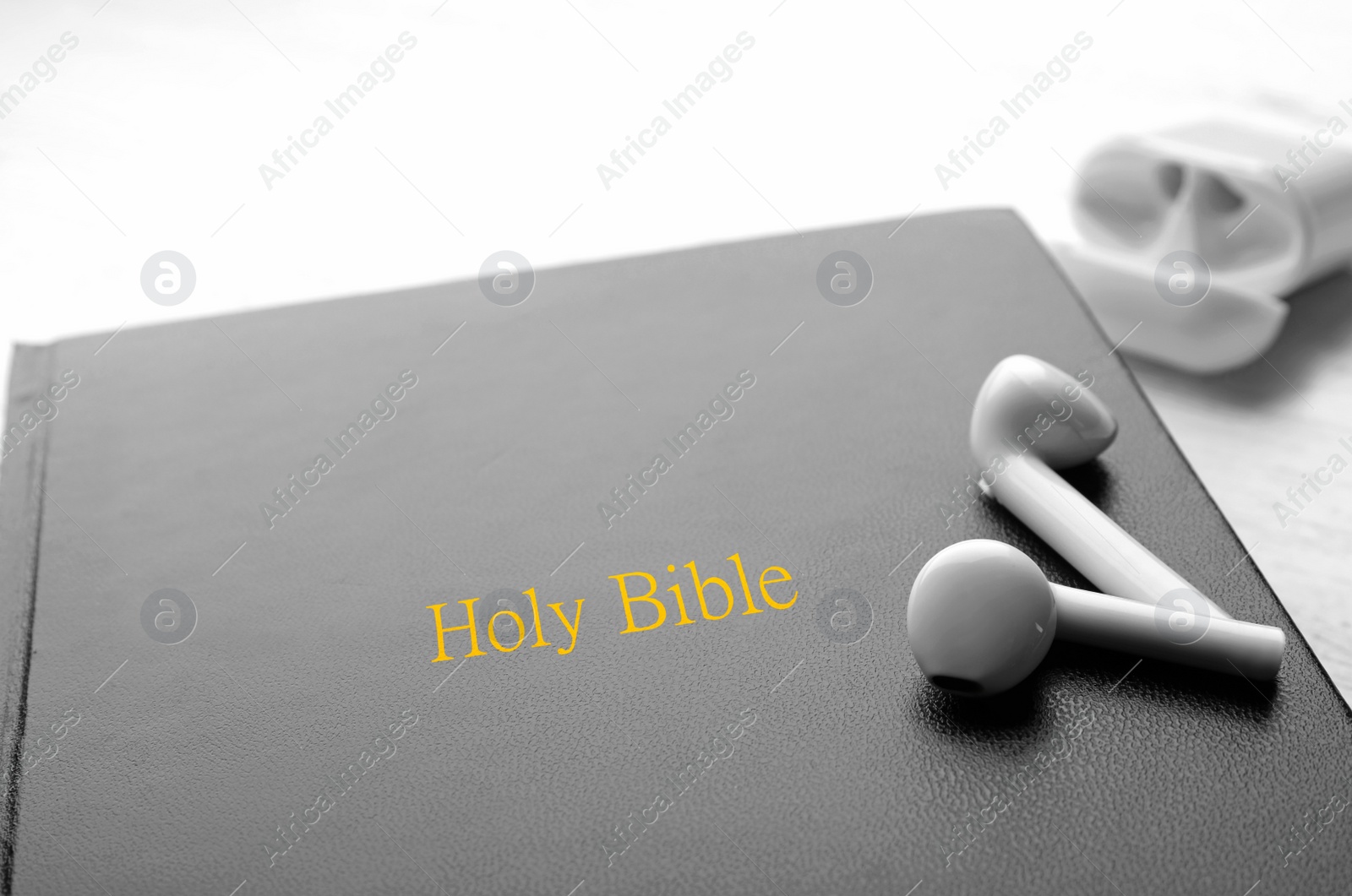 Photo of Bible and earphones on white table, closeup. Religious audiobook