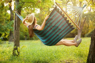 Photo of Young woman swinging in comfortable hammock at green garden