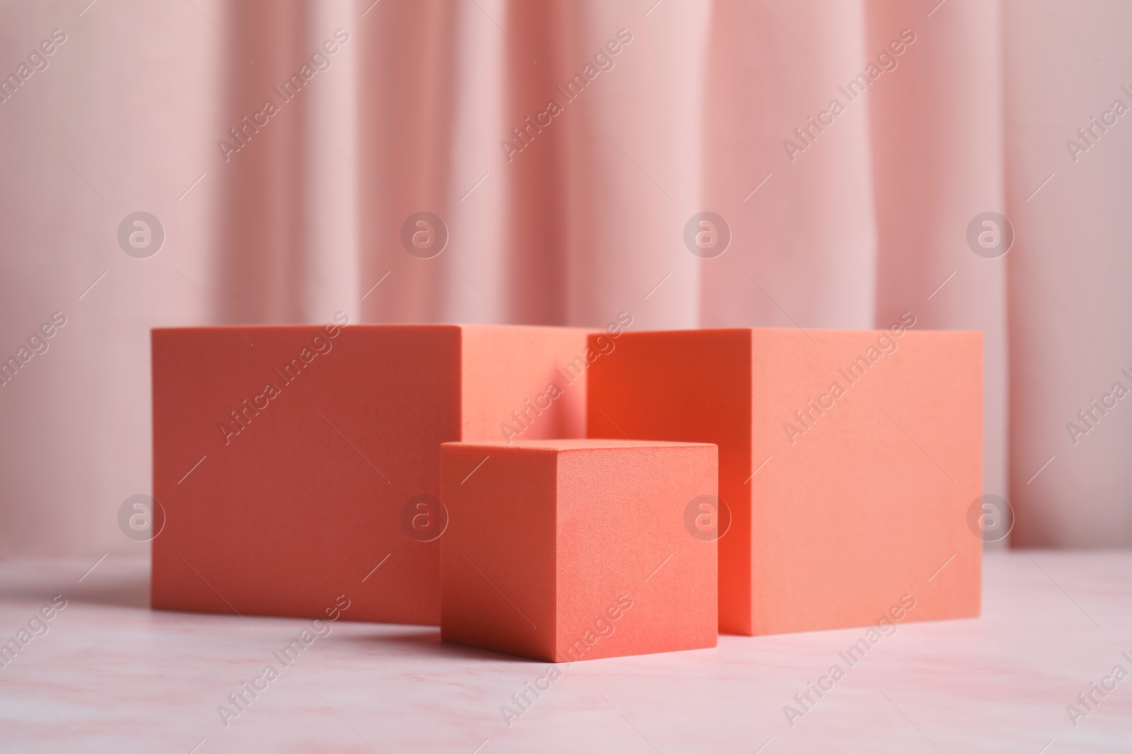 Photo of Orange cubes on pink marble table. Stylish presentation for product