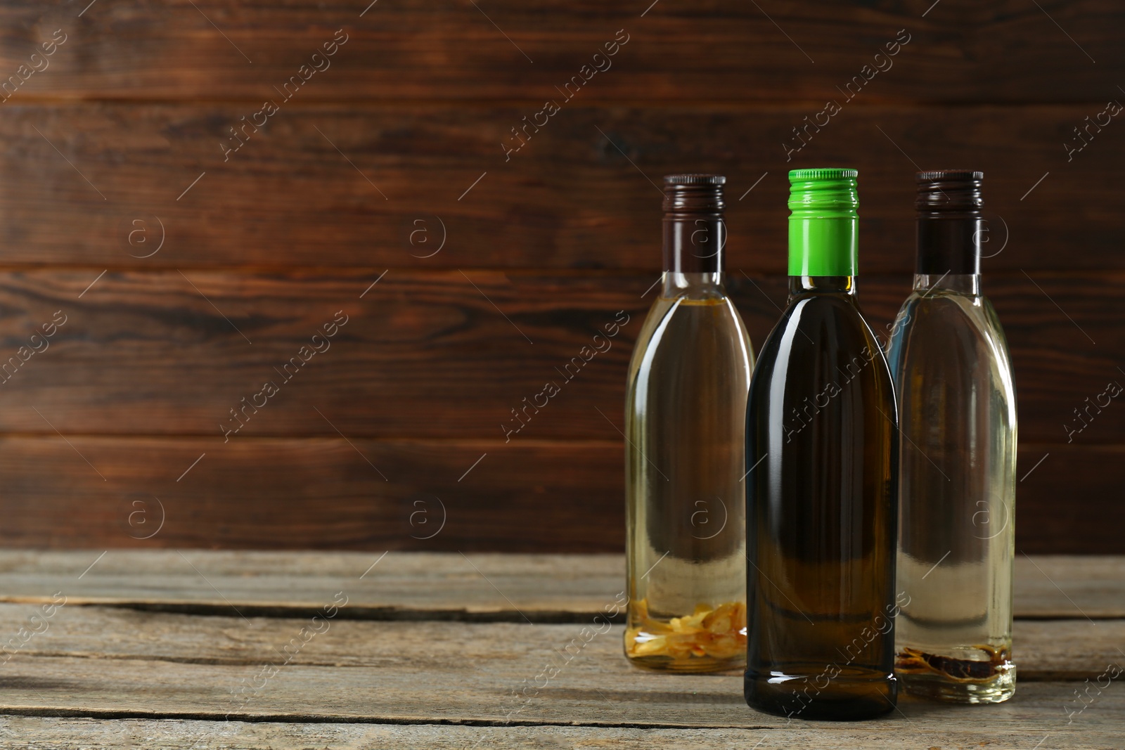 Photo of Vegetable fats. Different cooking oils in glass bottles on wooden table, space for text