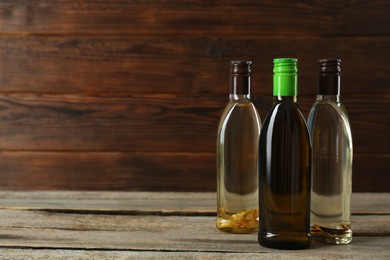 Vegetable fats. Different cooking oils in glass bottles on wooden table, space for text