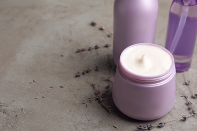 Photo of Set of hair care cosmetic products and dry lavender flowers on grey stone table, closeup. Space for text