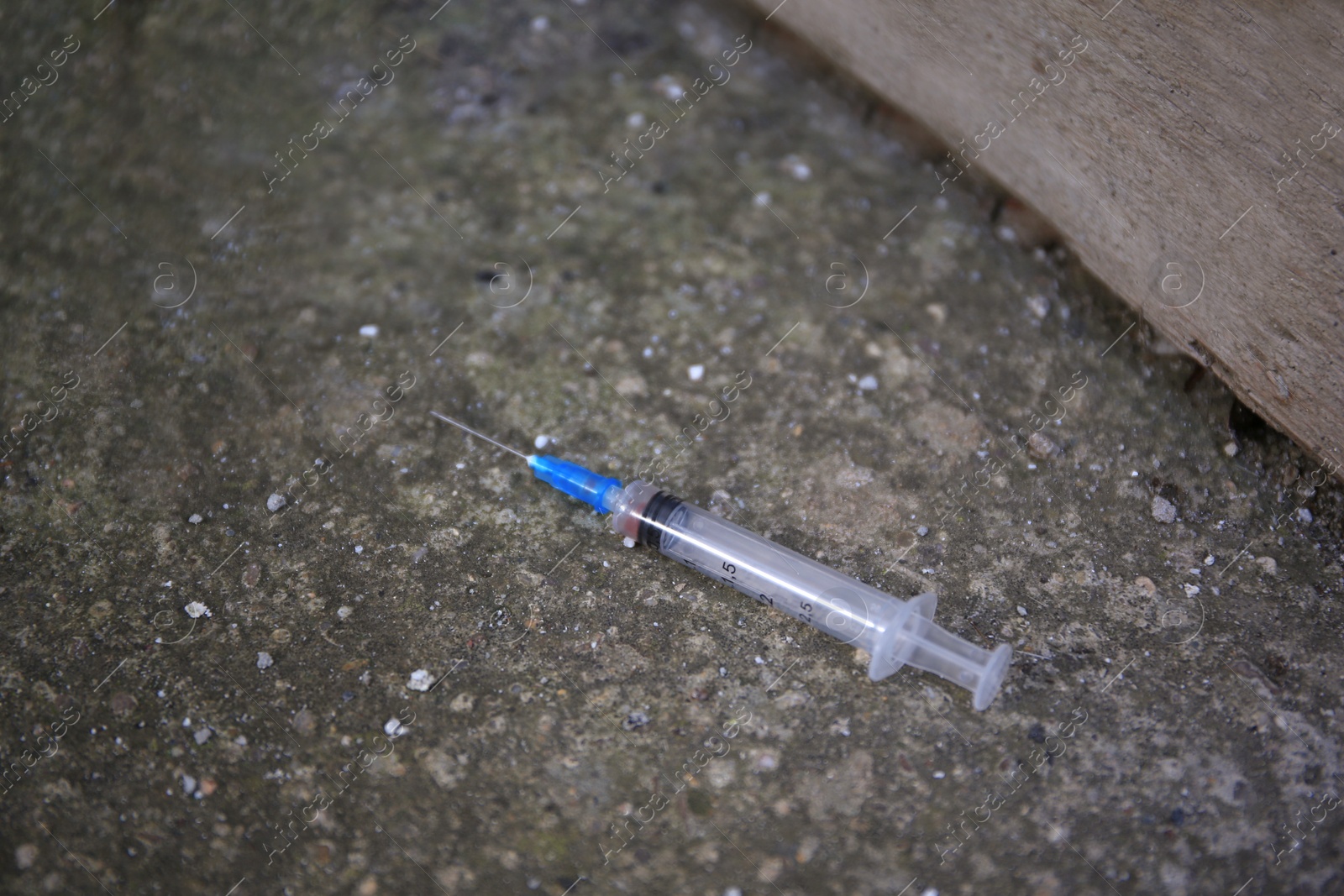 Photo of Disposable syringe with needle on concrete surface outdoors