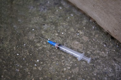 Photo of Disposable syringe with needle on concrete surface outdoors