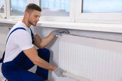 Photo of Professional plumber installing new heating radiator in room