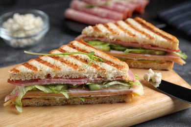 Photo of Tasty sandwich with ham on wooden board, closeup