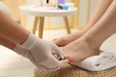 Professional pedicurist cutting client`s toenails with clipper in beauty salon, closeup