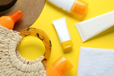 Photo of Suntan products, terry towel and bag on yellow background, flat lay