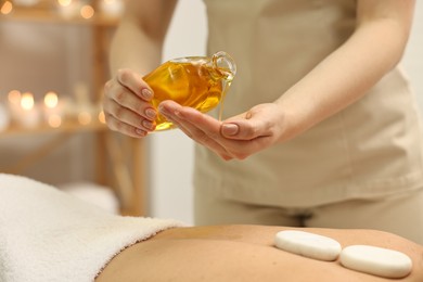 Photo of Aromatherapy. Woman receiving back massage with oil in spa salon, closeup