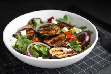 Photo of Delicious salad with roasted eggplant, cheese and arugula served on table, closeup