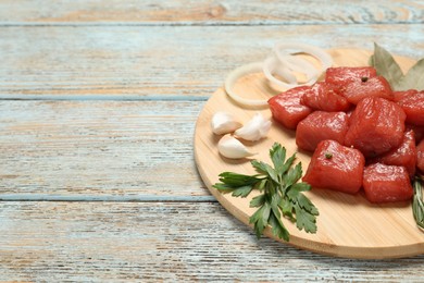 Photo of Raw beef meat and different ingredients for cooking delicious goulash on wooden table, space for text