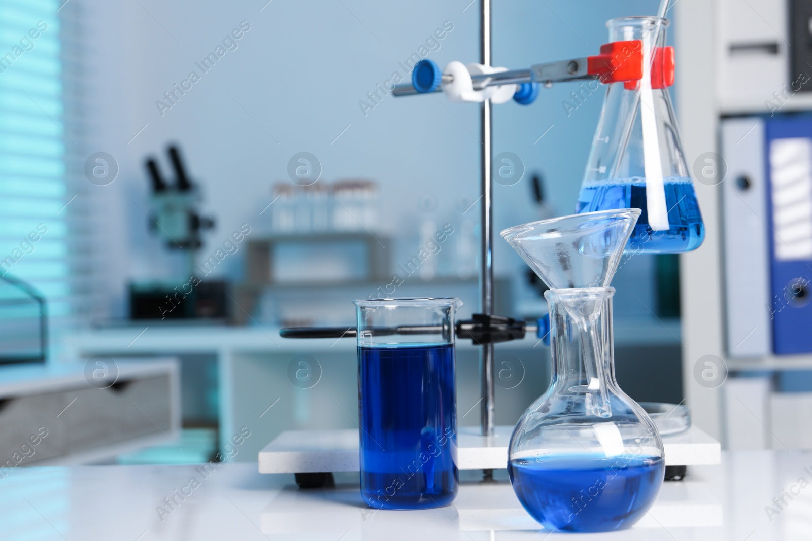 Photo of Laboratory analysis. Flasks and beaker with blue liquid on white table indoors