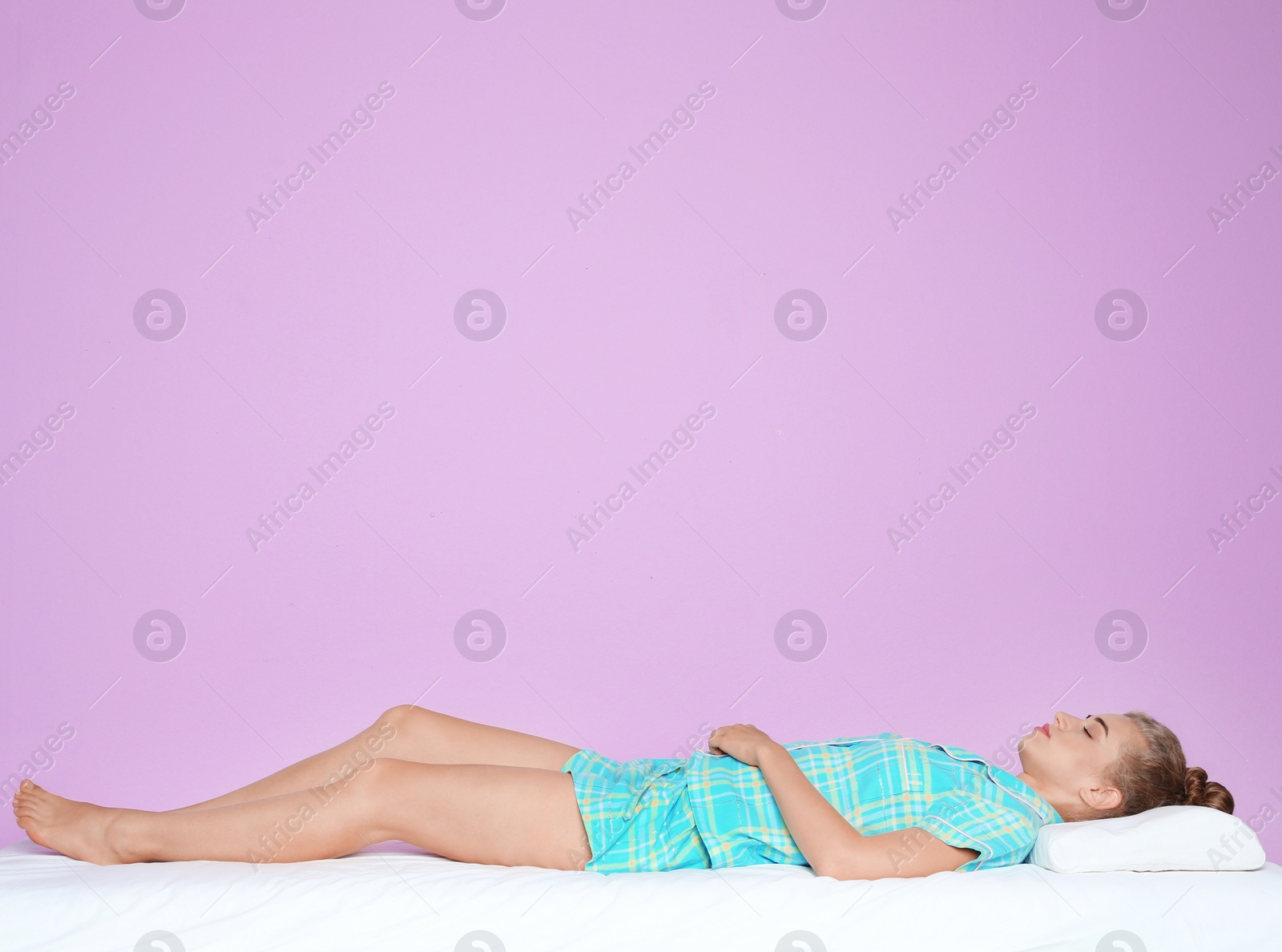 Photo of Beautiful woman sleeping with orthopedic pillow on bed against color background