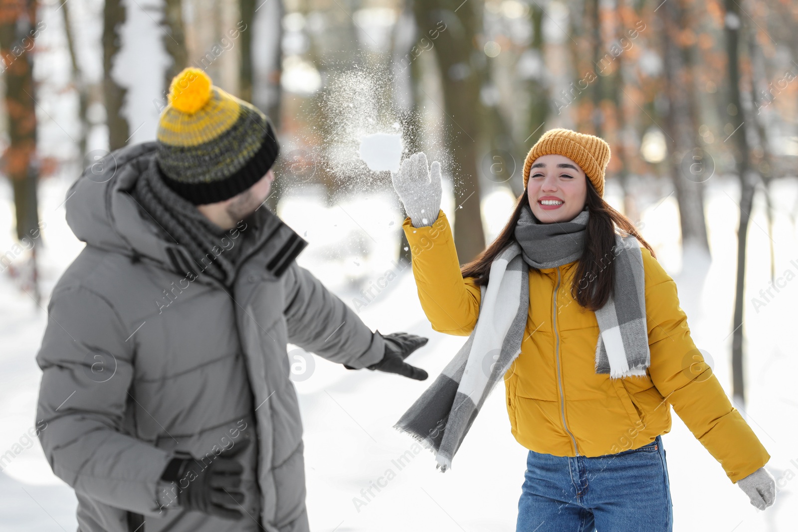 Photo of Happy couple playing snowballs on winter day outdoors