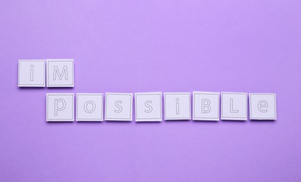 Photo of Motivation concept. Changing word from Impossible into Possible by removing paper with letters I and M on violet background, top view