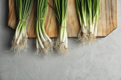 Photo of Fresh green onion on wooden board, top view
