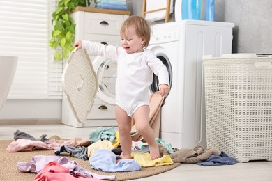 Photo of Little girl among baby clothes in bathroom