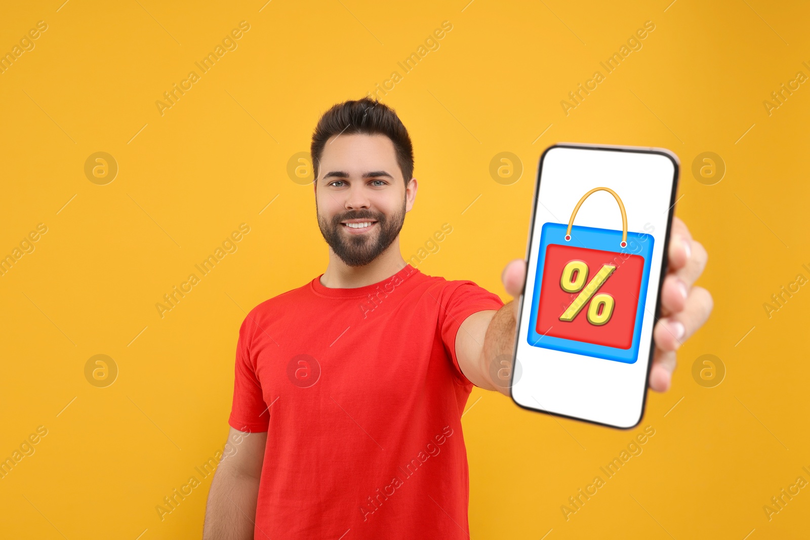 Image of Discount, offer, sale. Man showing mobile phone with illustration of bag and percent sign on screen, orange background