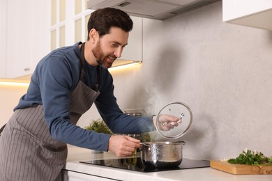 Photo of Man cooking soup on cooktop in kitchen
