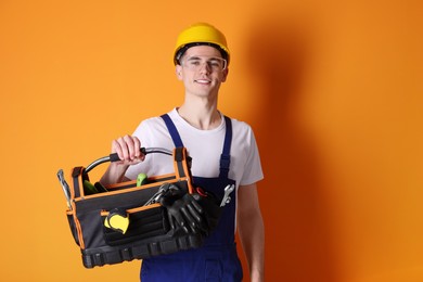 Photo of Professional repairman with tool box on orange background. Space for text